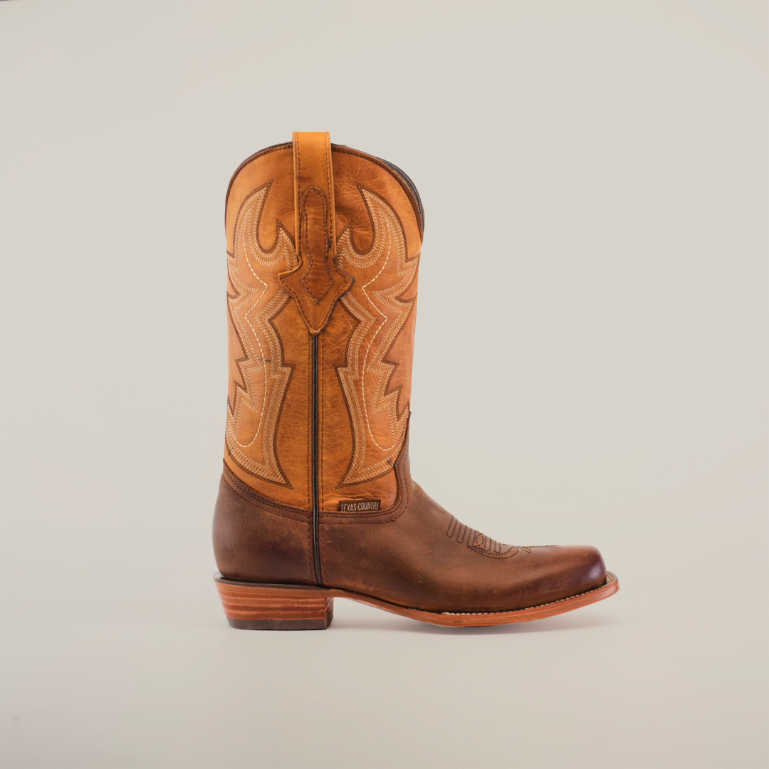 A pair of Azkar Tan - Wide Cutter Toe cowboy boots with intricate stitching is displayed against a plain white background. Made from premium cowhide leather, one boot stands upright while the other shows off its sole, emphasizing the detailed design.