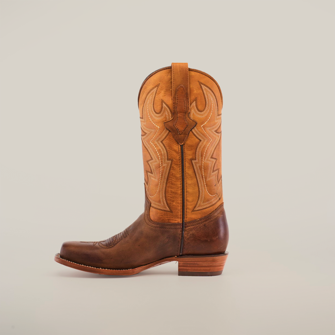 A pair of Azkar Tan - Wide Cutter Toe cowboy boots with intricate stitching is displayed against a plain white background. Made from premium cowhide leather, one boot stands upright while the other shows off its sole, emphasizing the detailed design.
