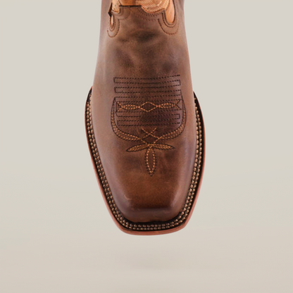 A pair of Azkar Tan - Wide Cutter Toe cowboy boots with intricate stitching is displayed against a plain white background. Made from premium cowhide leather, one boot stands upright while the other shows off its sole, emphasizing the detailed design.