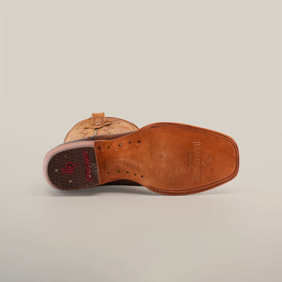 A pair of Azkar Tan - Wide Cutter Toe cowboy boots with intricate stitching is displayed against a plain white background. Made from premium cowhide leather, one boot stands upright while the other shows off its sole, emphasizing the detailed design.